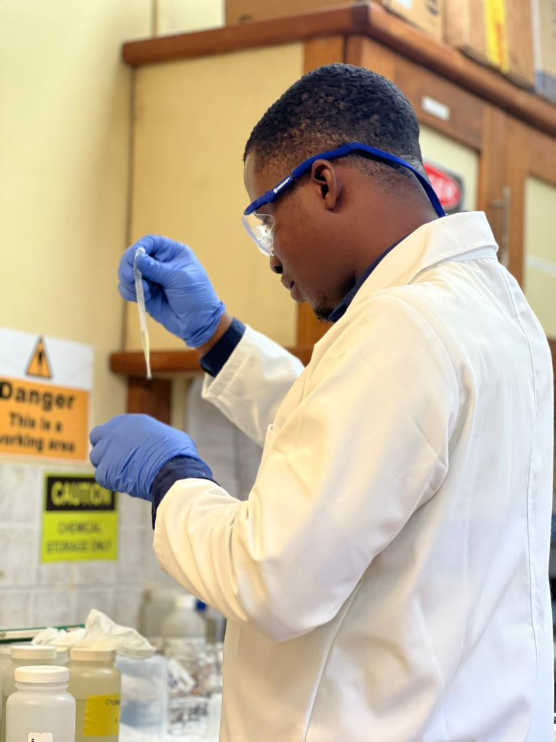 Israel is adding a reagent to a water sample as part of routine water quality analysis.